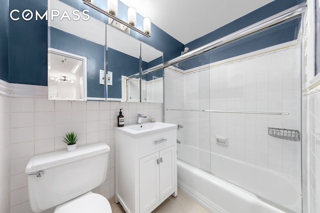 bathroom featuring toilet, vanity, shower / bath combination, and tile walls
