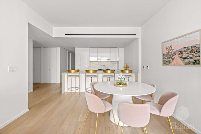 dining area featuring light wood finished floors and baseboards