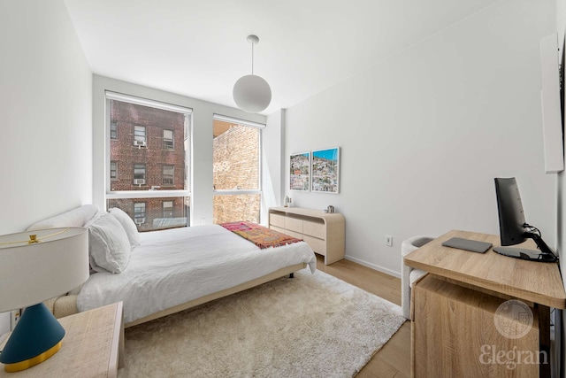 bedroom with wood finished floors, baseboards, and an office area