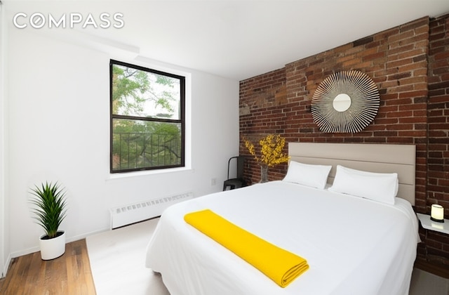 15 Jones St Unit 5H, New York City, NY 10014 - bedroom with radiator heating unit, wood finished floors, and brick wall
