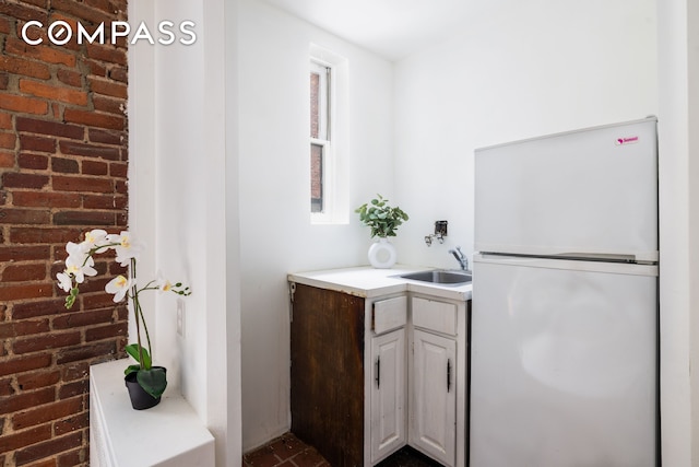 15 Jones St Unit 5H, New York City, NY 10014 - kitchen with freestanding refrigerator, a sink, brick wall, and light countertops