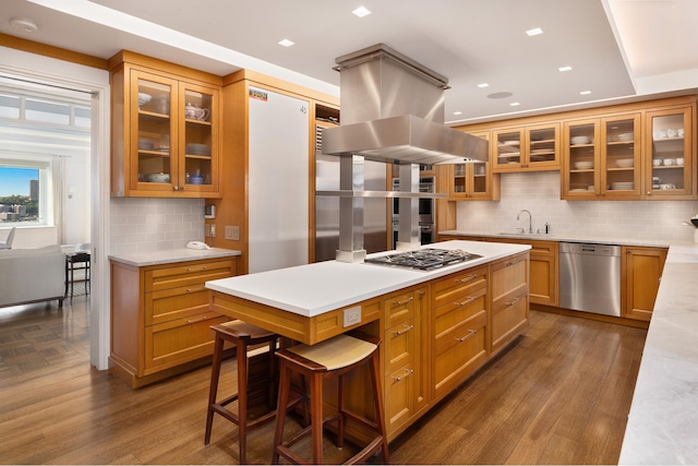 90 Riverside Dr Unit 14A, New York City, NY 10024 - kitchen featuring appliances with stainless steel finishes, decorative backsplash, island exhaust hood, light countertops, and dark wood-style flooring