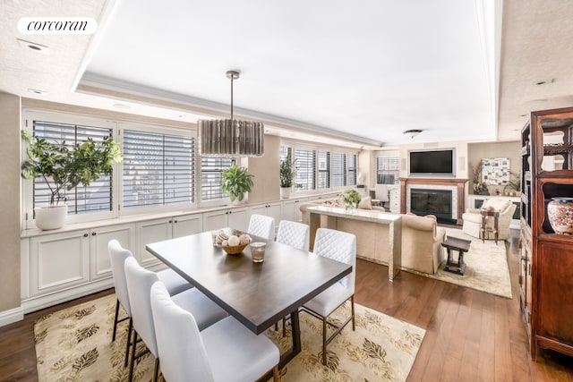 233 E 69th St Unit 14Klm, New York City, NY 10021 - dining area featuring light wood-style flooring, a glass covered fireplace, and a tray ceiling