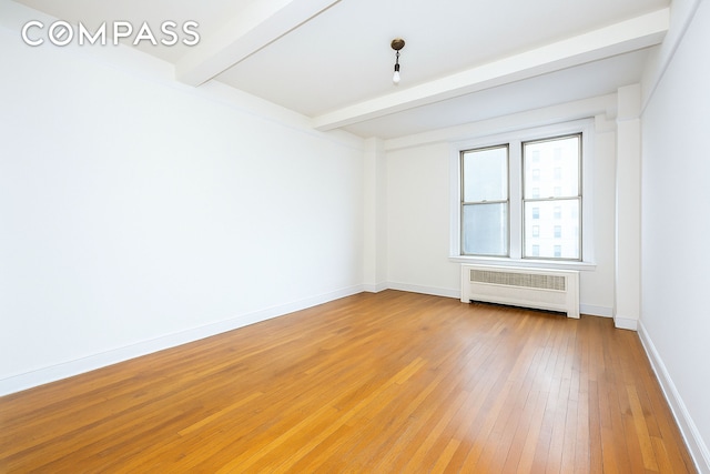 unfurnished room featuring radiator, beam ceiling, light wood finished floors, and baseboards