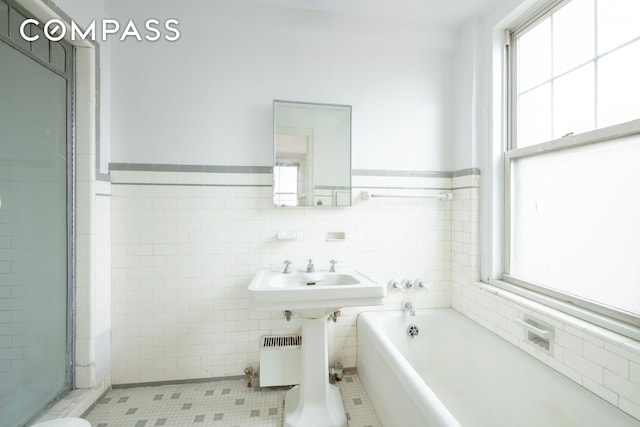 full bath with tile walls, a garden tub, tile patterned floors, wainscoting, and a shower stall