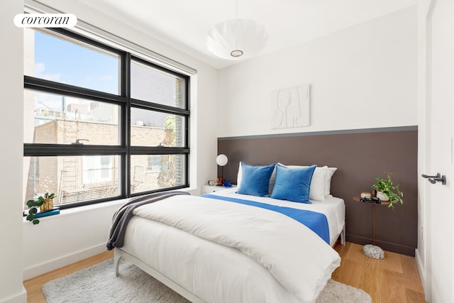 bedroom with light wood finished floors and baseboards