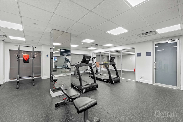 workout area with a paneled ceiling and baseboards