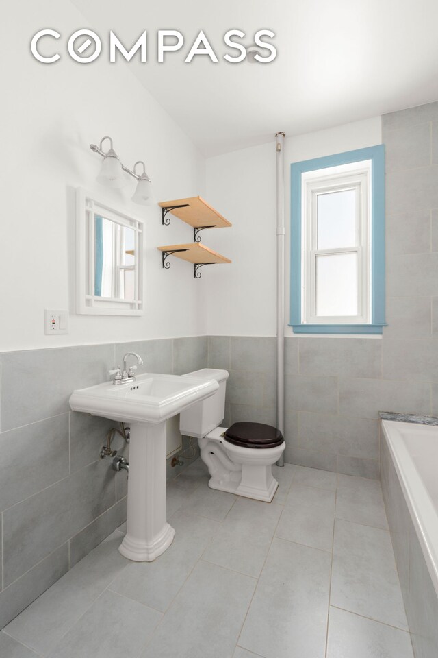 759 42nd St Unit 15, New York City, NY 11232 - full bathroom with tile walls, tiled tub, tile patterned floors, and a wainscoted wall