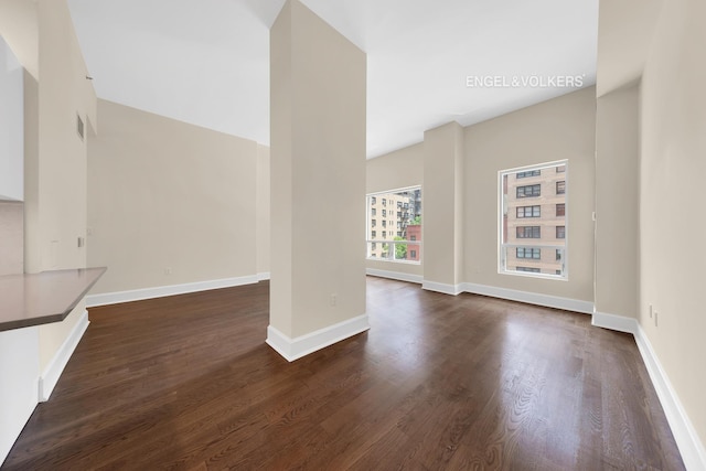 unfurnished living room featuring dark wood finished floors and baseboards