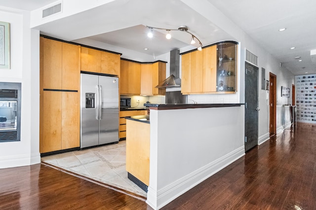 133 W 14th St Unit 6Ph, New York City, NY 10011 - kitchen featuring stainless steel refrigerator with ice dispenser, wall chimney range hood, light wood-type flooring, dark countertops, and baseboards