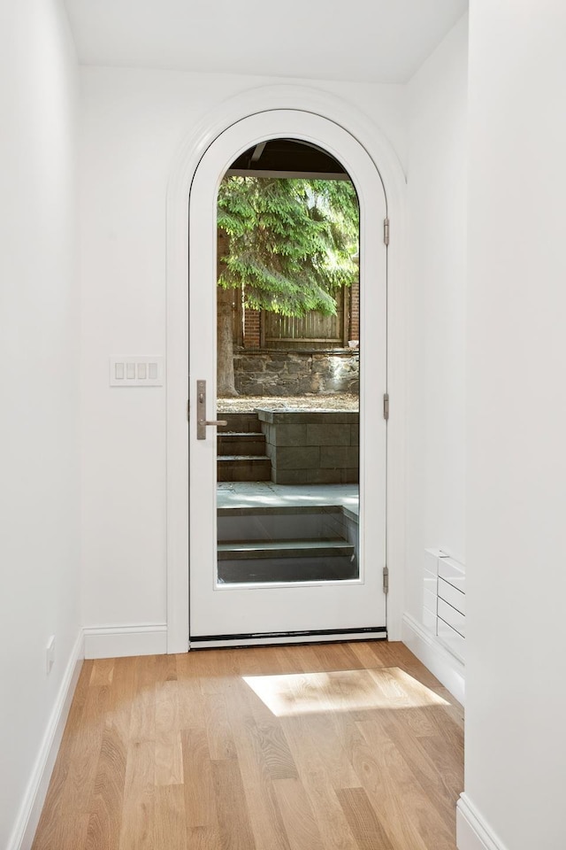 119 Henry St Unit 1, New York City, NY 11201 - doorway featuring light wood-type flooring, arched walkways, and baseboards