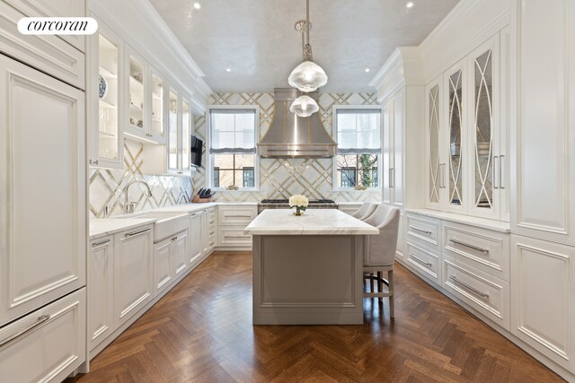 169 E 71st St, New York City, NY 10021 - kitchen featuring island exhaust hood, white cabinets, decorative backsplash, a sink, and ornamental molding