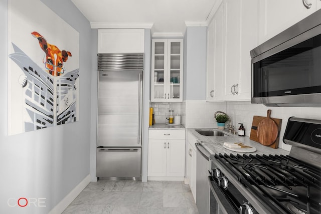 201 E 17th St Unit 32A, New York City, NY 10003 - kitchen featuring stainless steel appliances, light stone counters, light marble finish flooring, baseboards, and white cabinetry
