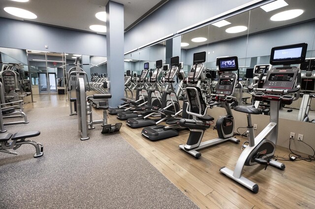 workout area featuring wood finished floors and a towering ceiling