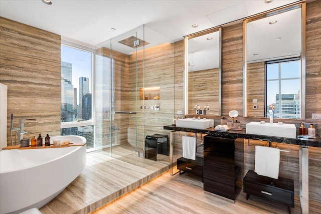 460 W 42nd St Unit Ph-1C, New York City, NY 10036 - bathroom featuring a shower stall, a freestanding tub, double vanity, a view of skyline, and recessed lighting
