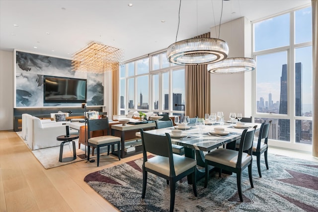460 W 42nd St Unit Ph-1C, New York City, NY 10036 - dining space featuring a chandelier, a wall of windows, a skyline view, wood finished floors, and recessed lighting