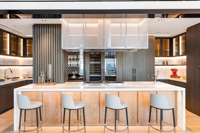 460 W 42nd St Unit Ph-1C, New York City, NY 10036 - kitchen with modern cabinets, a sink, light countertops, stainless steel gas cooktop, and glass insert cabinets