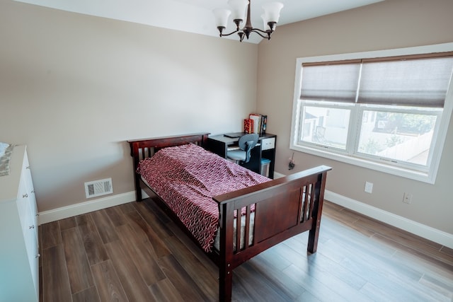 bedroom featuring a chandelier, wood finished floors, and baseboards
