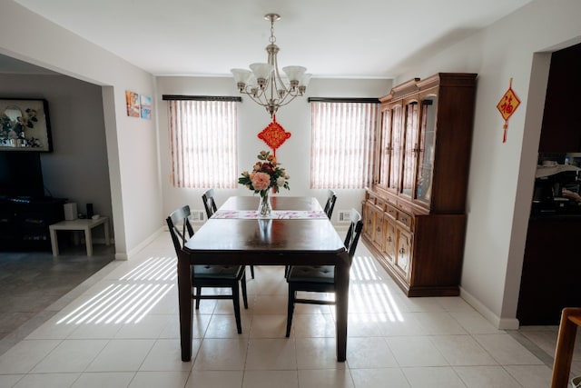 dining space with plenty of natural light, a chandelier, baseboards, and light tile patterned floors