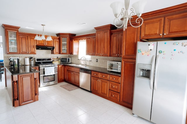 kitchen featuring appliances with stainless steel finishes, under cabinet range hood, a chandelier, and brown cabinets