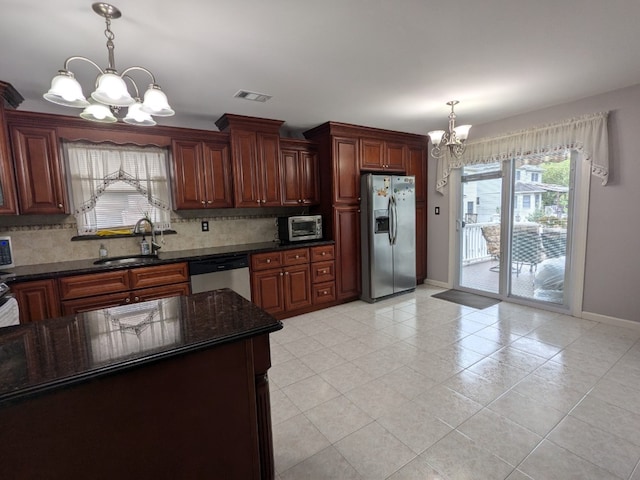 kitchen with a chandelier, appliances with stainless steel finishes, a sink, tasteful backsplash, and hanging light fixtures