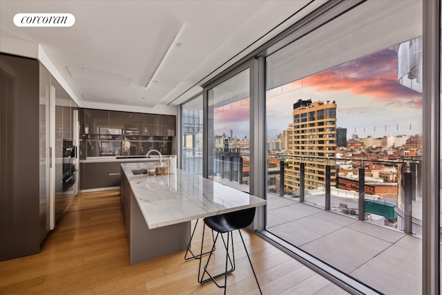 565 Broome St Unit S16B, New York City, NY 10013 - kitchen with light wood finished floors, a sink, a city view, an island with sink, and light stone countertops