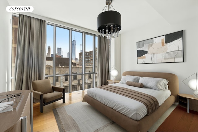 565 Broome St Unit S16B, New York City, NY 10013 - bedroom featuring a chandelier, a skyline view, and light wood finished floors