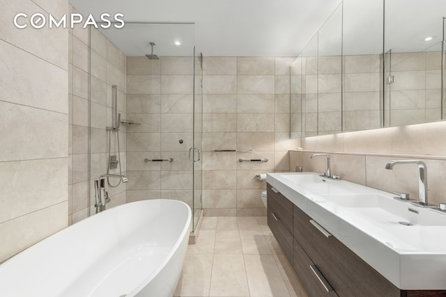 101 Leonard St Unit 2E, New York City, NY 10013 - full bathroom featuring tile walls, a stall shower, a freestanding tub, double vanity, and tile patterned floors