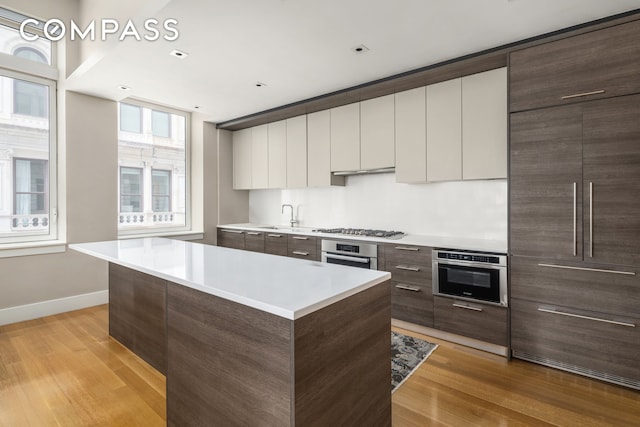kitchen featuring appliances with stainless steel finishes, modern cabinets, dark brown cabinets, and light countertops