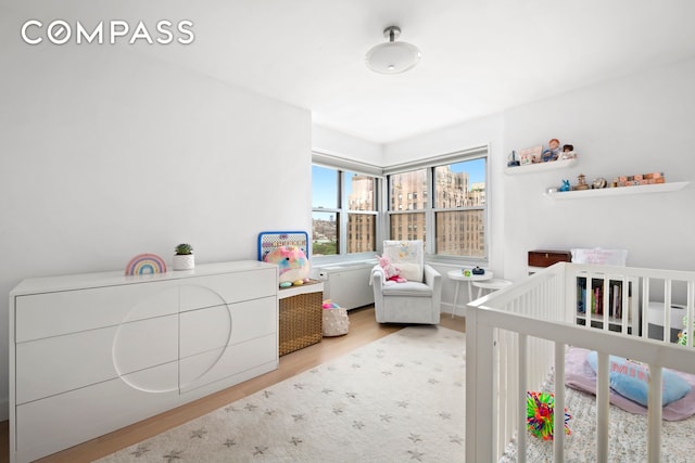 bedroom with a nursery area and wood finished floors