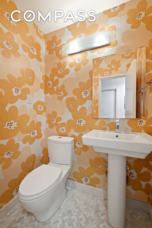 half bath featuring wallpapered walls, baseboards, and toilet