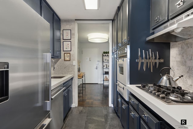 505 E 79th St Unit 17-D, New York City, NY 10075 - kitchen with stainless steel appliances, under cabinet range hood, blue cabinetry, and light countertops
