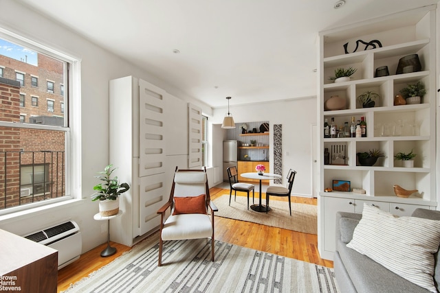 living area featuring light wood-style flooring and an AC wall unit