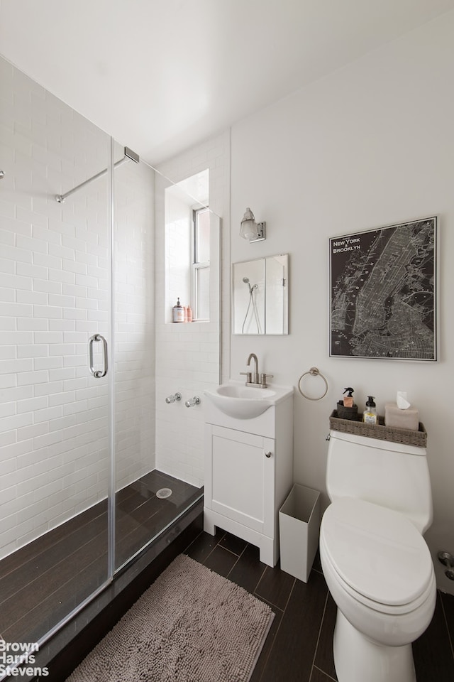 bathroom with toilet, a stall shower, and vanity