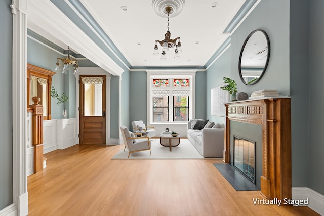 living room featuring a chandelier, a fireplace with flush hearth, wood finished floors, and crown molding