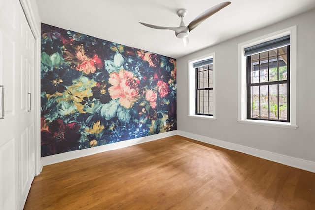 unfurnished room with baseboards, wood finished floors, and ceiling fan