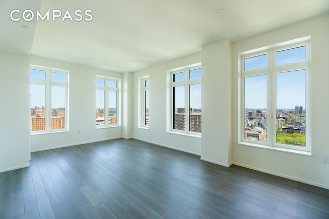unfurnished room with baseboards and dark wood finished floors