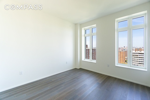 spare room with dark wood-type flooring and baseboards