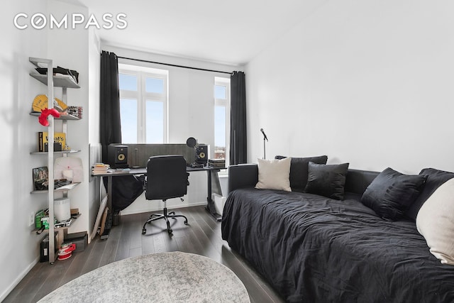 bedroom featuring an office area, dark wood-type flooring, and baseboards