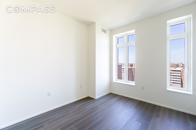 unfurnished room with plenty of natural light, dark wood-style flooring, and baseboards