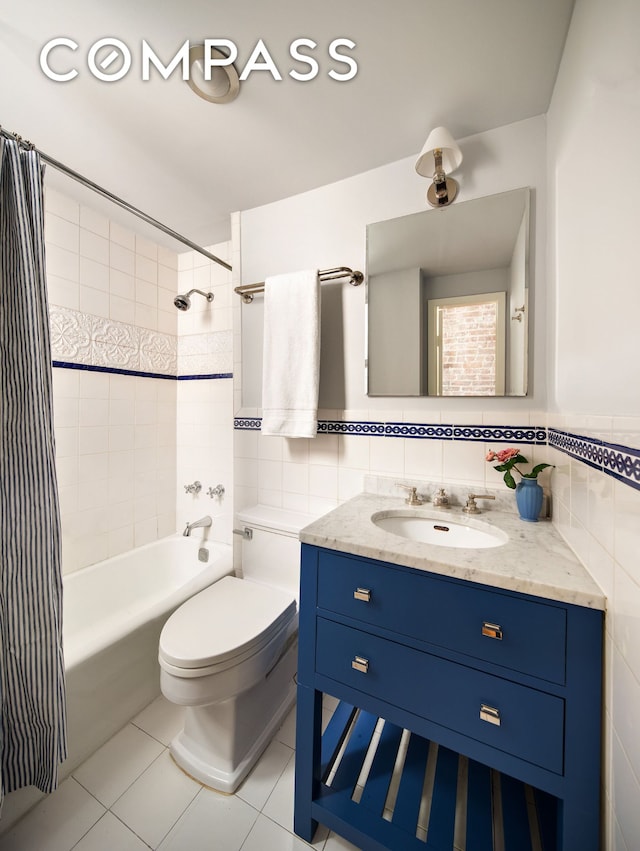 full bath with tile walls, tile patterned flooring, toilet, vanity, and shower / tub combo