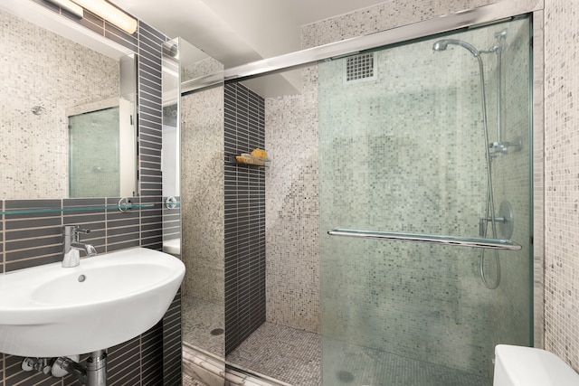 full bathroom featuring tile walls, toilet, a sink, and a shower stall