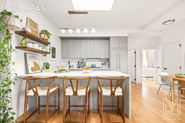 475 Washington Ave Unit 6F, New York City, NY 11238 - kitchen with gray cabinetry, light countertops, a breakfast bar, a peninsula, and open shelves