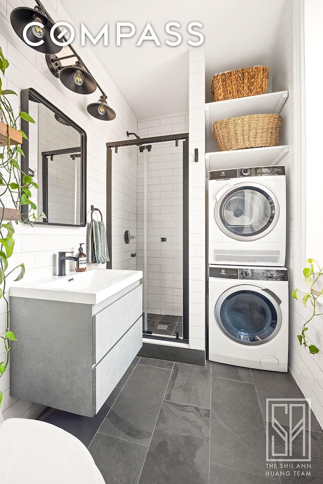 475 Washington Ave Unit 6F, New York City, NY 11238 - bathroom featuring stacked washer / drying machine, a shower stall, vanity, and tile walls
