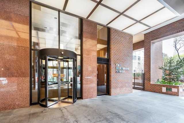 view of exterior entry featuring brick siding and a gate