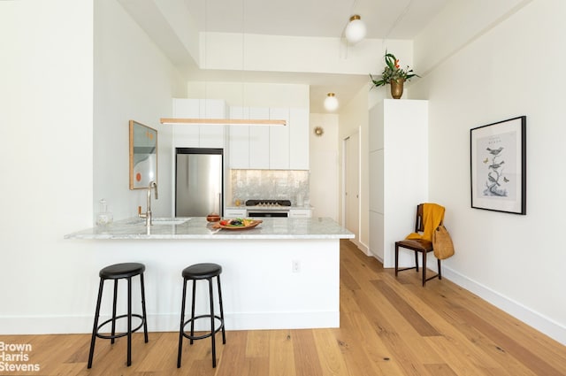 96 Schermerhorn St Unit 11F, New York City, NY 11201 - kitchen with high end refrigerator, white cabinetry, a peninsula, tasteful backsplash, and a kitchen bar