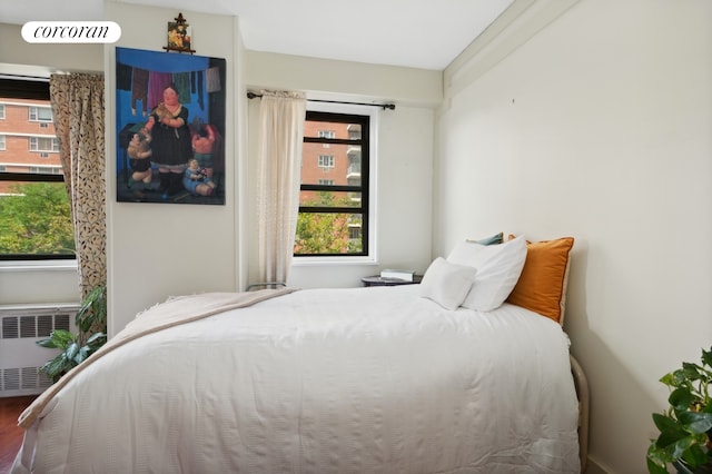 39-60 54th St Unit B3, New York City, NY 11377 - bedroom featuring radiator heating unit, multiple windows, and wood finished floors