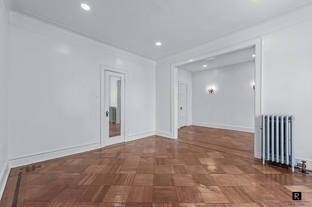 spare room with radiator, recessed lighting, and baseboards