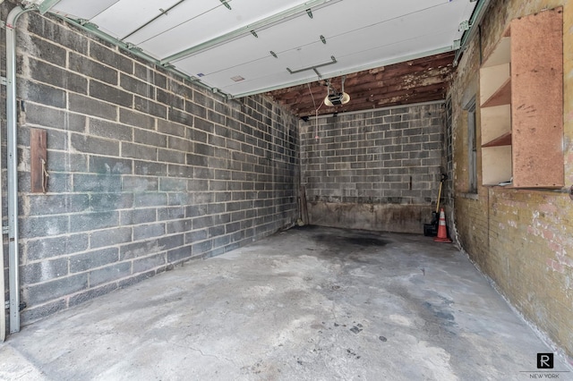 garage featuring a garage door opener and concrete block wall