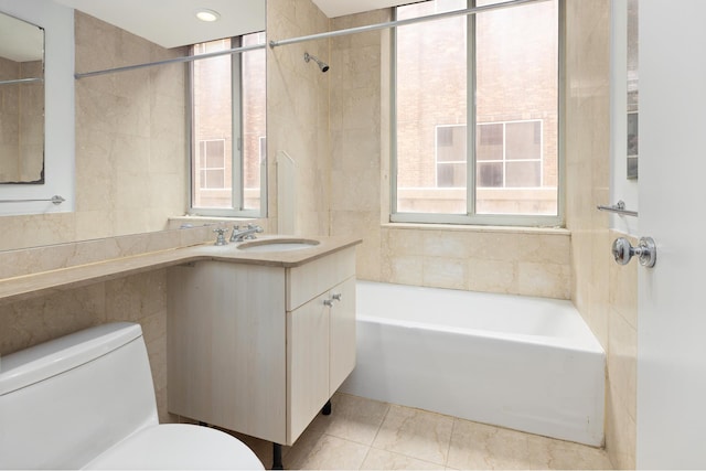 full bath featuring toilet, tile walls, a tub to relax in, and vanity